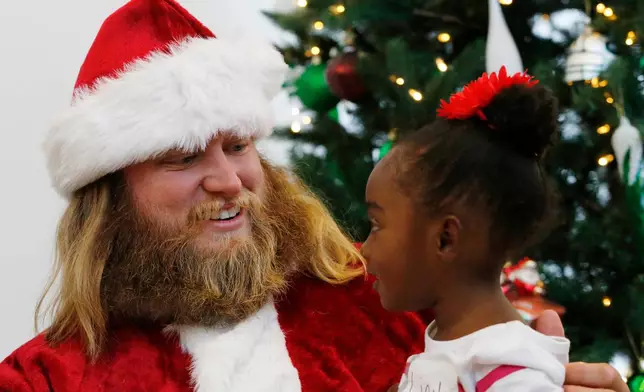 FILE - Lian Taylor, 2, right, of Bayonne, N.J., sits on the lap of New York Jets center Nick Mangold posing as Santa Claus during the team's holiday party for military families, Friday, Dec. 4, 2015, in Florham Park, N.J. (AP Photo/Julio Cortez, File)