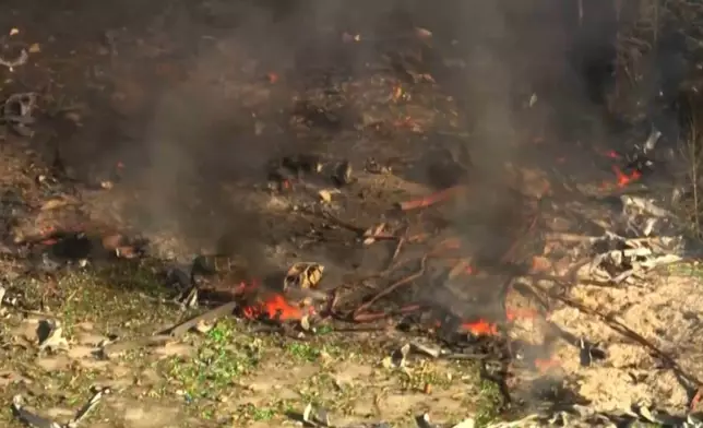Smoke fills the air as debris covers the ground and vehicles after a powerful blast ripped through a military explosives manufacturing plant in Hickman County, Tenn., on Friday, Oct. 10, 2025. (WTVF-TV via AP)