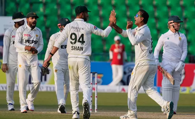 Pakistan's Noman Ali, second right, celebrates with teammates after taking the wicket of South Africa's Kyle Verreynne, right, during the second day of the first test cricket match between Pakistan and South Africa, in Lahore, Pakistan, Monday, Oct. 13, 2025. (AP Photo/K.M. Chaudary)