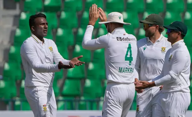 South Africa's Senuran Muthusamy, left, celebrates with teammates after taking the wicket of Pakistan's Mohammad Rizwan during the second day of the first test cricket match between Pakistan and South Africa, in Lahore, Pakistan, Monday, Oct. 13, 2025. (AP Photo/K.M. Chaudary)