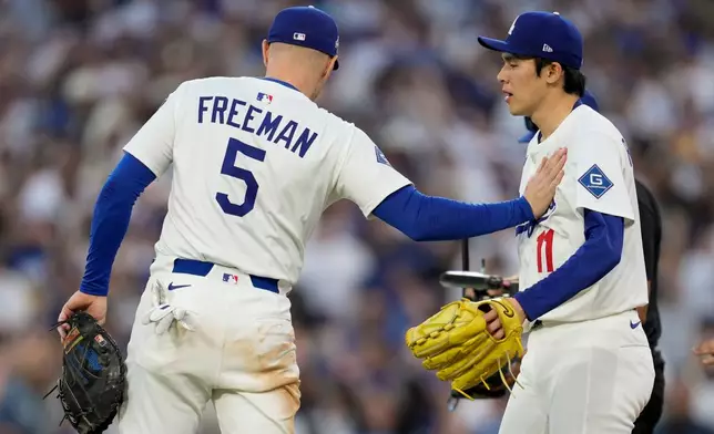 Los Angeles Dodgers pitcher Roki Sasaki and first baseman Freddie Freeman celebrate their win against the Milwaukee Brewers in Game 3 of baseball's National League Championship Series, Thursday, Oct. 16, 2025, in Los Angeles. (AP Photo/Ashley Landis)