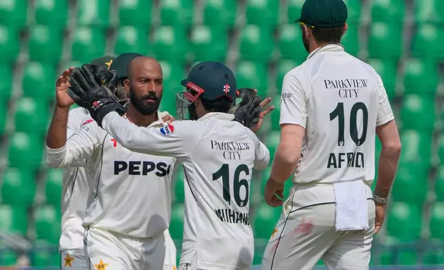 Pakistan's Sajid Khan, left, and teammates celebrate after the dismissal of South Africa's Ryan Rickelton during the fourth day of the first test cricket match between Pakistan and South Africa, in Lahore, Pakistan, Wednesday, Oct. 15, 2025. (AP Photo/K.M. Chaudary)