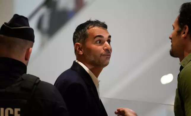 Defendant Aurelien Poirson-Atlan, center, arrives at the courtroom as ten people go on trial over cyberbullying of Brigitte Macron after they allegedly made "malicious" comments online spreading claims that President Emmanuel Macron 's wife is a man. Monday, Oct. 27, 2025 in Paris. (AP Photo/Michel Euler)