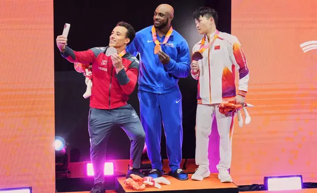 Gold medal, Donnell Whittenburg of the United States, center, poses with silver medal, Adem Asil of Turkey, left, and bronze medal, Lan Xingyu of China after competing in the men's rings final during the 53rd Artistic Gymnastics World Championships in Jakarta, Indonesia, Friday, Oct. 24, 2025. (AP Photo/Achmad Ibrahim)