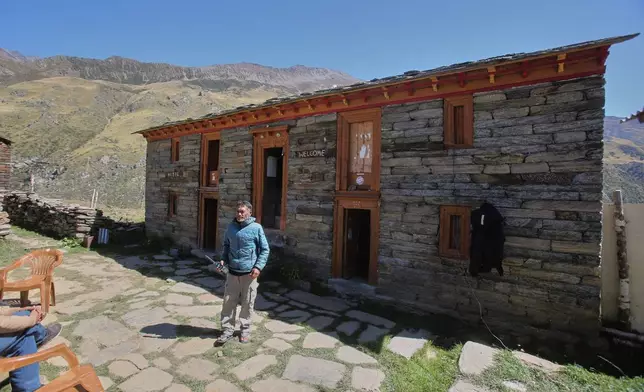 Raju Martolia holds a satellite phone outside his homestay in Martoli village in the northern Indian Himalayan state of Uttarakhand, on Oct. 4, 2025. (AP Photo/Satish Sharma)