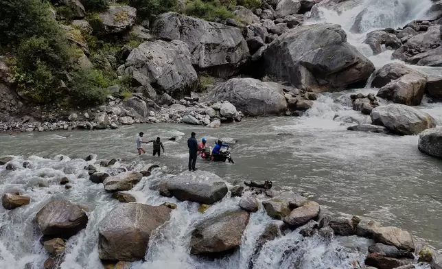 Motorcyclists make their way across a fast-flowing stream, on their way to the Nanda Devi base camp in Rilkot village, in the northern Indian Himalayan state of Uttarakhand, on Oct. 6, 2025. (AP Photo/Satish Sharma)