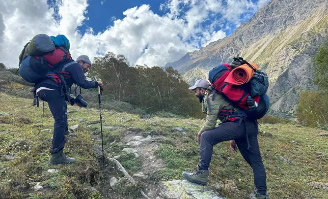 Trekking guides Pawan Koranga, left, and Raju Goswmi stop to catch their breath as they accompany a client to the Nanda Devi base camp, in the northern Indian Himalayan state of Uttarakhand, on Sept. 30, 2025. (AP Photo/Satish Sharma)