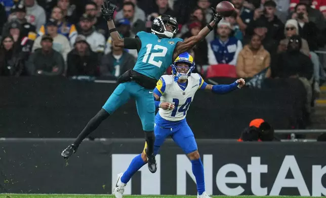 Jacksonville Jaguars wide receiver Travis Hunter (12) reaches to catch the ball as Los Angeles Rams cornerback Cobie Durant (14) challenges during the first half of an NFL football game between the Los Angeles Rams and the Jacksonville Jaguars in London, Sunday, Oct. 19, 2025. (AP Photo/Kin Cheung)
