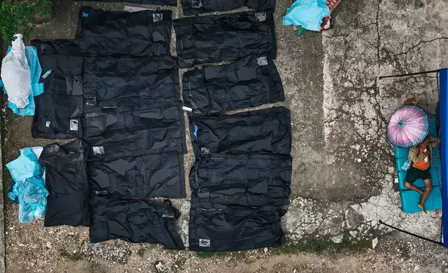 A man rests beside bodies of victims of an earthquake outside Cebu Provincial Hospital in Bogo City, Philippines, Wednesday, Oct. 1, 2025. (AP Photo/Jacqueline Hernandez)