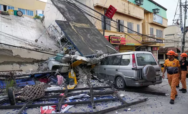 Firemen walk beside a collapsed building caused by a recent strong earthquake in Bogo city, Cebu Province, Central Philippines on Thursday, Oct. 2, 2025. (AP Photo/Aaron Favila)