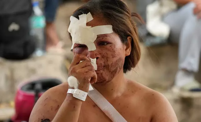 Earthquake survivor Jesiel Malinao sits beside the coffins of her two sons on Thursday, Oct. 2, 2025 after a strong earthquake on Tuesday caused a landslide that toppled their hillside homes in Bogo city, Cebu Province, Central Philippines. (AP Photo/Aaron Favila)