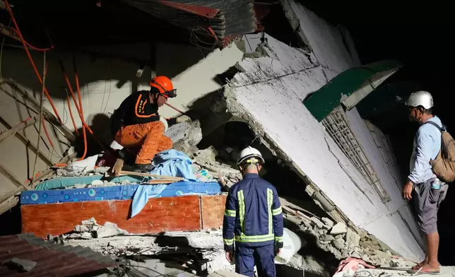Rescuers check for survivors in the ruins of a collapsed building, Wednesday, Oct. 1, 2025 after a strong earthquake struck Bogo city, Cebu Province, Central Philippines. (AP Photo/Aaron Favila)