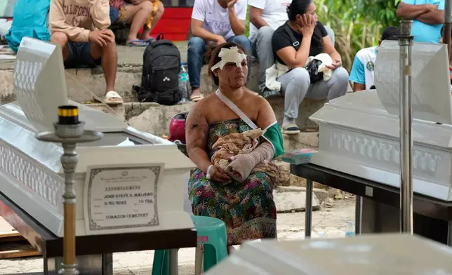 Earthquake survivor Jesiel Malinao sits beside the coffins of her two sons on Thursday, Oct. 2, 2025 after a strong earthquake on Tuesday caused a landslide that toppled their hillside homes in Bogo city, Cebu Province, Central Philippines. (AP Photo/Aaron Favila)