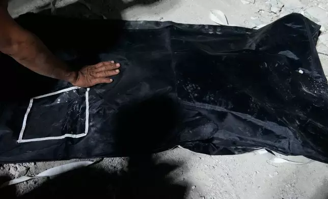 Isagani Geliig touches the body of his son that was recovered from the ruins of a collapsed building, Wednesday, Oct. 1, 2025 after a strong earthquake struck Bogo city, Cebu Province, Central Philippines. (AP Photo/Aaron Favila)