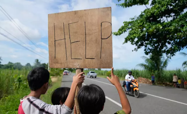 Earthquake survivors hold a "Help" sign along a road Thursday, Oct. 2, 2025, days after a strong quake struck in Medellin, Cebu Province, Central Philippines. (AP Photo/Aaron Favila)