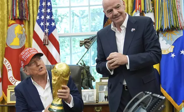 FILE - President Donald Trump holds the FIFA World Cup Winners Trophy as FIFA President Gianni Infantino looks on during an announcement in the Oval Office of the White House, Aug. 22, 2025, in Washington. (AP Photo/Jacquelyn Martin, File)