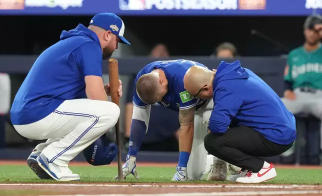 Toronto Blue Jays manager John Schneider, left, and a trainer talk with Nathan Lukes, centre, after he was hit by the ball during first inning American League Championship Series baseball action against the Seattle Mariners in Toronto on Sunday, Oct. 12, 2025. (Chris Young/The Canadian Press via AP)