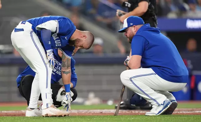 Toronto Blue Jays manager John Schneider, front right, talks with Nathan Lukes, front left, after Lukes was hit by the ball dduring the first inning in Game 1 of baseball's American League Championship Series against the Seattle Mariners in Toronto, Sunday, Oct. 12, 2025. (Frank Gunn/The Canadian Press via AP)