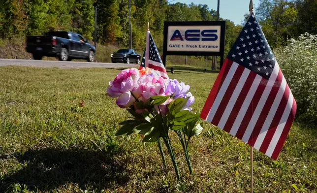 Flowers and flags rest at the entrance to Accurate Energetic Systems after an explosion on Friday, killed 16 people in McEwen, Tenn. Sunday, Oct. 12, 2025. (AP Photo/George Walker IV)