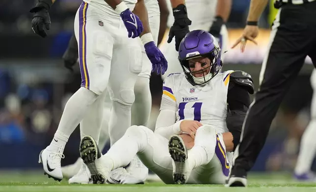 Minnesota Vikings quarterback Carson Wentz (11) sits on the ground after a hit during the second half of an NFL football game against the Los Angeles Chargers Thursday, Oct. 23, 2025, in Inglewood, Calif. (AP Photo/Gregory Bull)