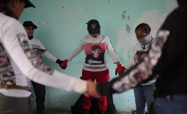 Relatives of missing people, part of a group called the Guerreros Buscadores, pray before inspecting an area where they suspect bodies may be buried, in the Valle de los Olivos neighborhood of Guadalajara, Mexico, Tuesday, Oct. 14, 2025. (AP Photo/Eduardo Verdugo)