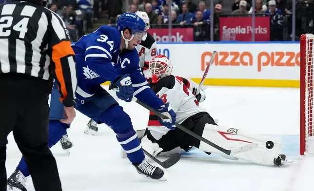 Toronto Maple Leafs centre Auston Matthews (34) misses the net as New Jersey Devils goaltender Jake Allen (34) looks on during second period NHL hockey action in Toronto, Tuesday, Oct. 21, 2025. (Nathan Denette/The Canadian Press via AP)