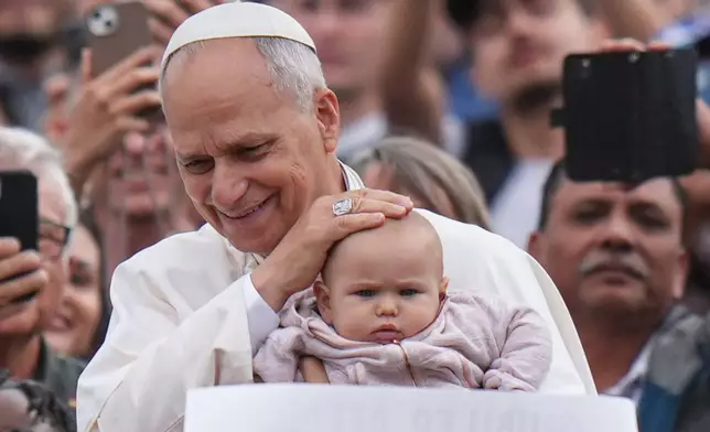 Pope Leo XIV blesses a child at the end of a Mass for the Jubilee of Migrants and Missionaries in St. Peter's Square at the Vatican, Sunday, Oct. 5, 2025. (AP Photo/Alessandra Tarantino)