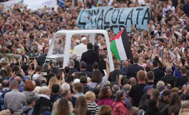 Pope Leo XIV rides on his popemobile next to a Palestinian flag at the end of a Mass for the Jubilee of Migrants and Missionaries in St. Peter's Square at the Vatican, Sunday, Oct. 5, 2025. (AP Photo/Alessandra Tarantino)
