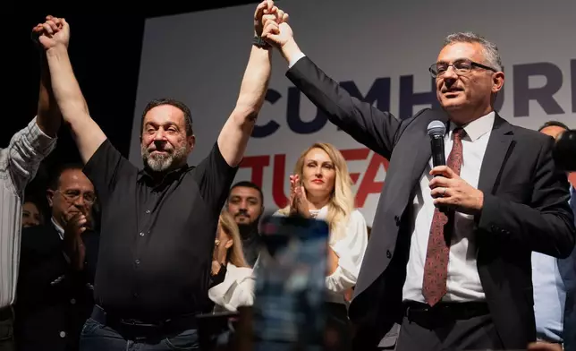 Turkish Cypriot newly elected leader Tufan Erhurman, right, and Serdar Denktash, son of the former Turkish Cypriot leader Rauf Denktash, celebrate after winning the leadership election in the Turkish occupied northern part of the divided capital Nicosia, Cyprus, Sunday, Oct. 19, 2025. (AP Photo/Nedim Enginsoy)