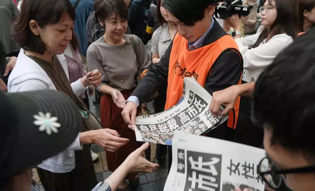 FILE - A worker distributes copies of special edition newspaper issued after Sanae Takaichi won the ruling Liberal Democratic Party leadership vote in Tokyo, Oct. 4, 2025. (AP Photo/Ayaka McGill, File)