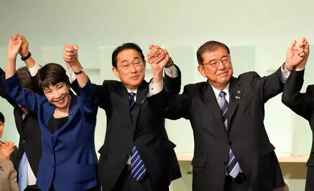 FILE - Shigeru Ishiba, right, with Sanae Takaichi, left, and Japan's Prime Minister Fumio Kishida, center, celebrates after Ishiba was elected as new the head of Japan's ruling party at the Liberal Democratic Party's leadership election, Sept. 27, 2024, in Tokyo. (AP Photo/Hiro Komae, Pool, File)