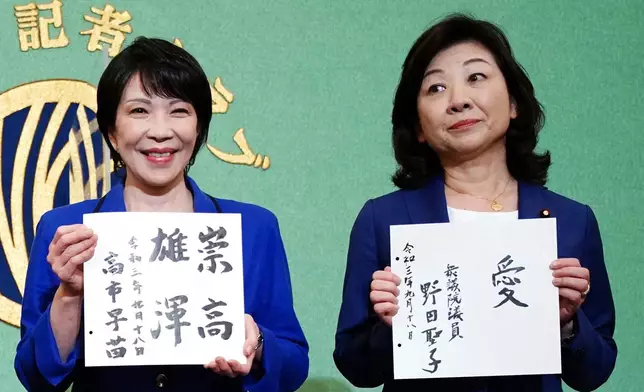 FILE - Sanae Takaichi, left, and Seiko Noda, right, both former internal affairs ministers and candidates for the presidential election of the ruling Liberal Democratic Party, show their motto on cards, during a debate session held by the Japan National Press Club, Sept. 18, 2021, in Tokyo. (AP Photo/Eugene Hoshiko, Pool, File)