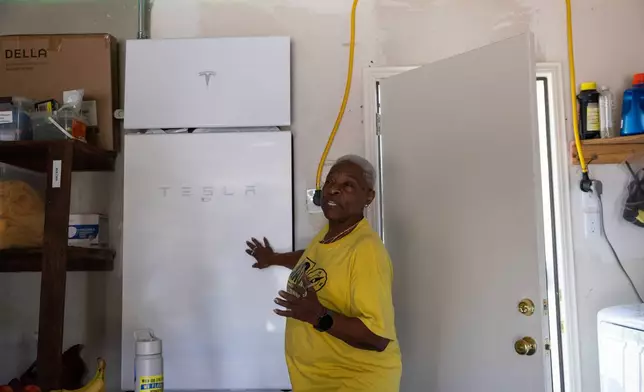 Doris Brown, Hub home captain, gives a tour of her garage and shows a Tesla Powerwall battery that is charged by the solar panels on top of her home, Wednesday, Oct. 8, 2025, in Houston. (AP Photo/Antranik Tavitian)
