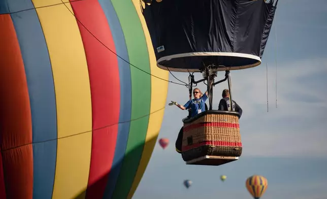 FILE - A balloon crew waves to the crowd over Albuquerque, N.M., on the second day of the Balloon Fiesta Oct. 3, 2021. (Adria Malcolm/The Albuquerque Journal via AP, File)