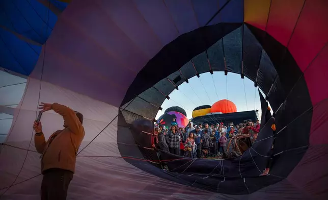 FILE - Pilot Mark Meyer, of North Carolina, takes a photo inside the Carnival special shape balloon as a crowd gathers around during the Albuquerque International Balloon Fiesta's Special Shape Rodeo and balloon launch at Balloon Fiesta Park in Albuquerque, N.M., Oct. 10, 2024. (Chancey Bush/The Albuquerque Journal via AP, File)