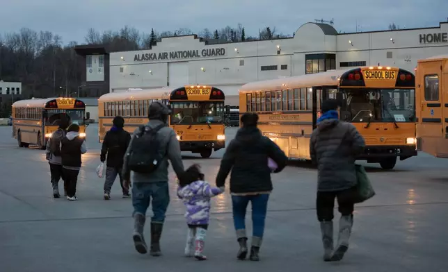In this photo provided by the Alaska National Guard, Alaskans from West Coast communities board buses after arriving at Joint Base Elmendorf-Richardson, Alaska, Wednesday, Oct. 15, 2025. (Alejandro Pena/Alaska National Guard via AP)