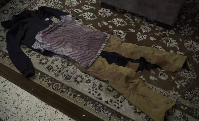 Blood-stained clothes, which Wafa Jazar, 42, says were worn by her 14-year-old son, Ahmad Jazar, when he was shot by Israeli soldiers, are laid out for a photo in a room of their home in the West Bank village of Sebastia, March 11, 2025. (AP Photo/Leo Correa)
