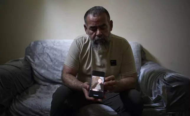 Ashraf Gharbieh, 45, holds a phone showing a photo of his 14-year-old son, Mahmoud Gharbieh, who was killed in an Israeli airstrike in the Jenin refugee camp, as he sits for a portrait at a friend's house on the outskirts of the West Bank city of Jenin, April 21, 2025. (AP Photo/Leo Correa)