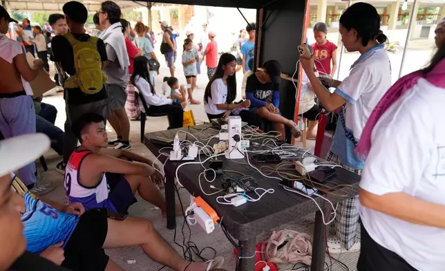 Survivors of Tuesday's earthquake charge their phones on Thursday, Oct. 2, 2025 in San Remigio, Cebu Province, Central Philippines. (AP Photo/Aaron Favila)