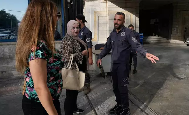 A Syrian policeman checks women at the entrance of Latakia's Governor building where the voting for a parliamentary election is taking place, in the coastal city of Latakia, Syria, Sunday, Oct. 5, 2025. (AP Photo/Hussein Malla)