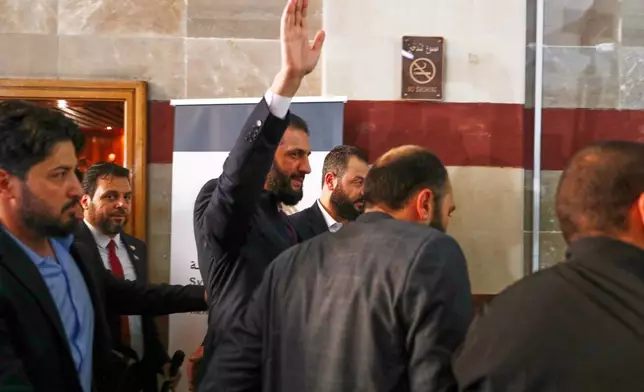 Syrian interim President Ahmad al-Sharaa waves as he enters a polling station where electoral college members are voting in a parliamentary election in Damascus, Syria, Sunday, Oct. 5, 2025. (AP Photo/Omar Sanadiki)