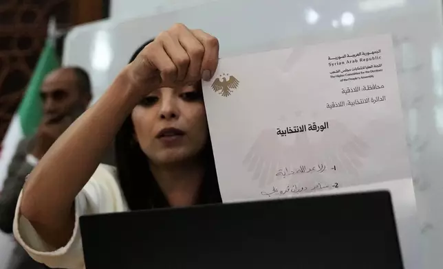 A Syrian election official shows a ballot paper during the counting of ballots, shortly after polling stations closed at Latakia's Governor building, in the coastal city of Latakia, Syria, Sunday, Oct. 5, 2025. (AP Photo/Hussein Malla)