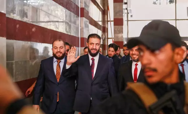 Syrian interim President Ahmad al-Sharaa waves as he enters a polling station where electoral college members are voting in a parliamentary election in Damascus, Syria, Sunday, Oct. 5, 2025. (AP Photo/Omar Sanadiki)