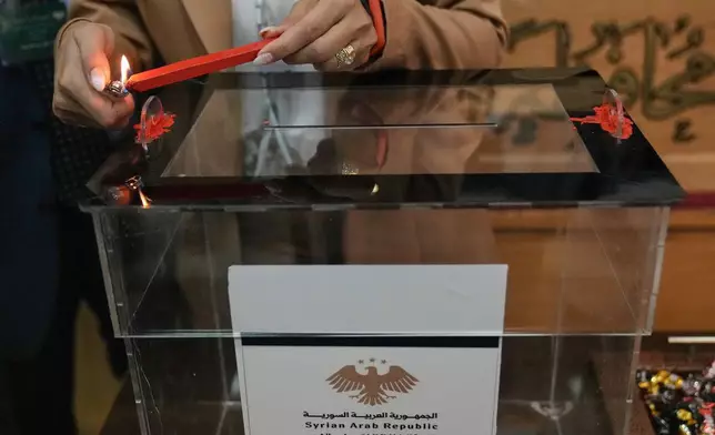 A Syrian election official burns red wax to stamp a ballot box ahead of the parliamentary elections at Latakia's Governor ballot station, in the coastal city of Latakia, Syria, Sunday, Oct. 5, 2025. (AP Photo/Hussein Malla)