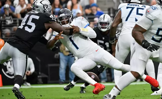 Tennessee Titans quarterback Cam Ward (1) fumbles the ball while hit by Las Vegas Raiders linebacker Devin White (45) during the first half of an NFL football game, Sunday, Oct. 12, 2025, in Las Vegas. (AP Photo/David Becker)