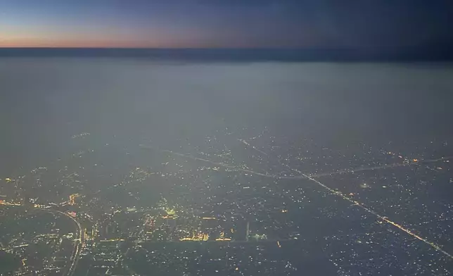 A layer of smog hangs over the skyline as seen from an aircraft window in New Delhi, India, Saturday, Oct. 25, 2025. (AP Photo/Yirmiyan Arthur)