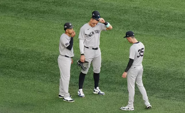 New York Yankees outfielders, from left, Trent Grisham, Aaron Judge and Cody Bellinger talk in the outfield as the Yankees make a pitching change during the third inning against the Toronto Blue Jays in Game 1 of baseball's American League Division Series, Saturday, Oct. 4, 2025, in Toronto. (Chris Young/The Canadian Press via AP)