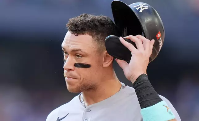 New York Yankees outfielder Aaron Judge (99) walks back to the dugout at the end of the top of the first inning in Game 1 of baseball's American League Division Series against the Toronto Blue Jays, Saturday, Oct. 4, 2025, in Toronto. (Nathan Denette/The Canadian Press via AP)