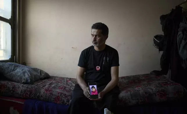 Iyad Rajab holds a phone with a photo of his 10-year-old son, Saddam Rajab, who was killed by Israeli fire, as he sits on the boy’s bed, in the West Bank city of Tulkarem, March 17, 2025. (AP Photo/Leo Correa)