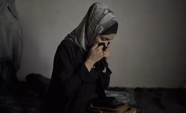 Anwar al-Heimouni, 29, smells the gloves of her 12-year-old son, Ayman al-Heimouni, who was killed by Israeli fire, in their home in the West Bank city of Hebron, March 26, 2025. (AP Photo/Leo Correa)